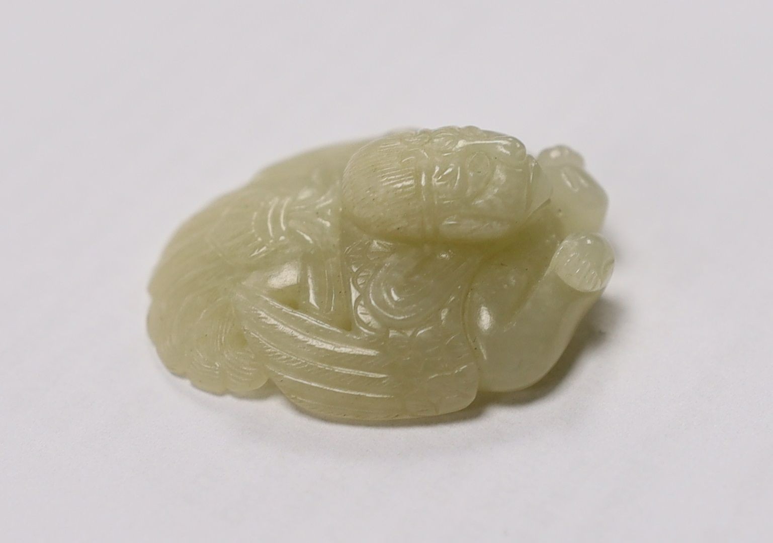 A Chinese pale celadon jade mount carved as a mythical half-man half-bird creature, 18th/19th century, 3.8cm high